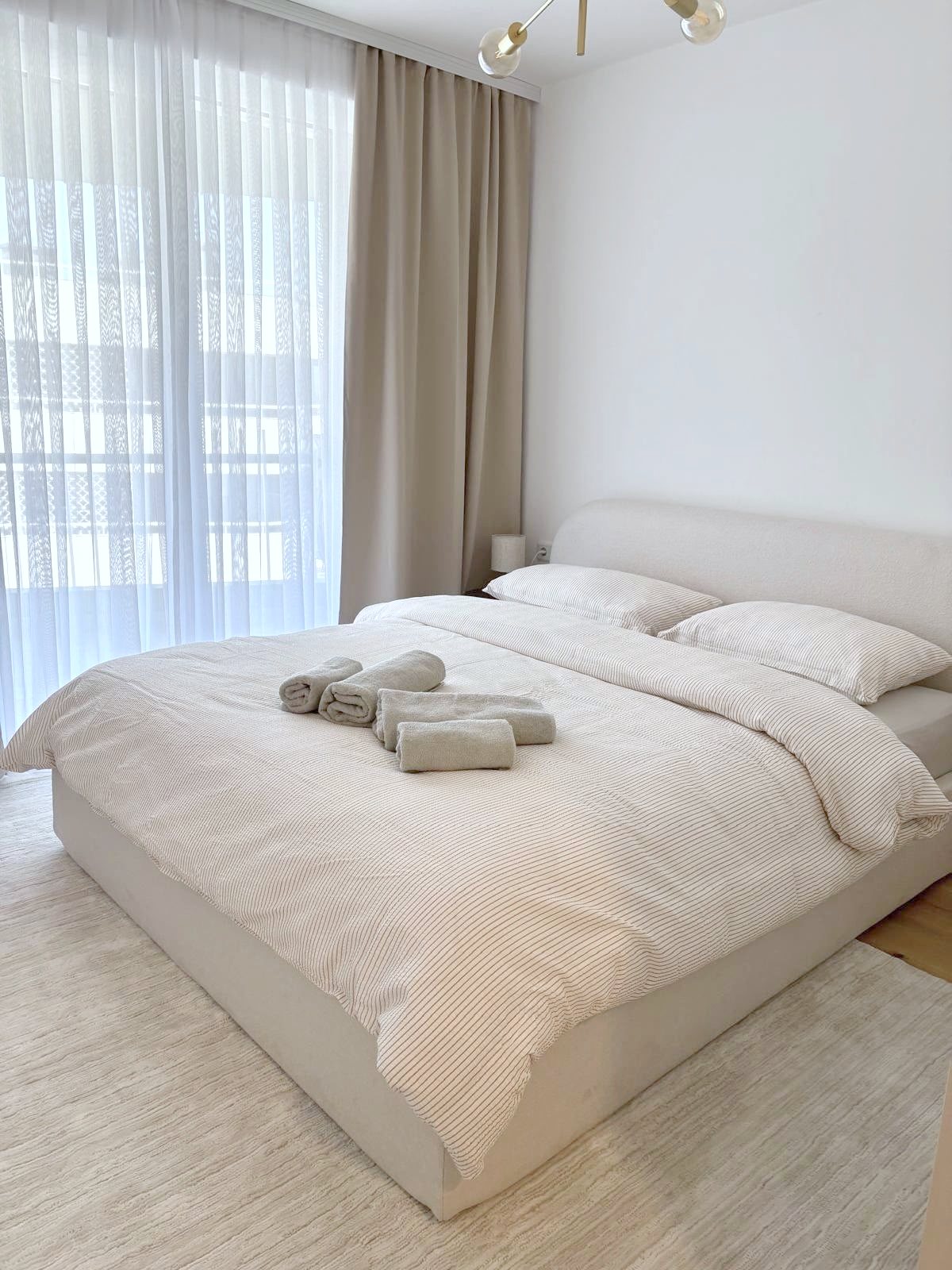 Bedroom with upholstered double bed and linen curtains