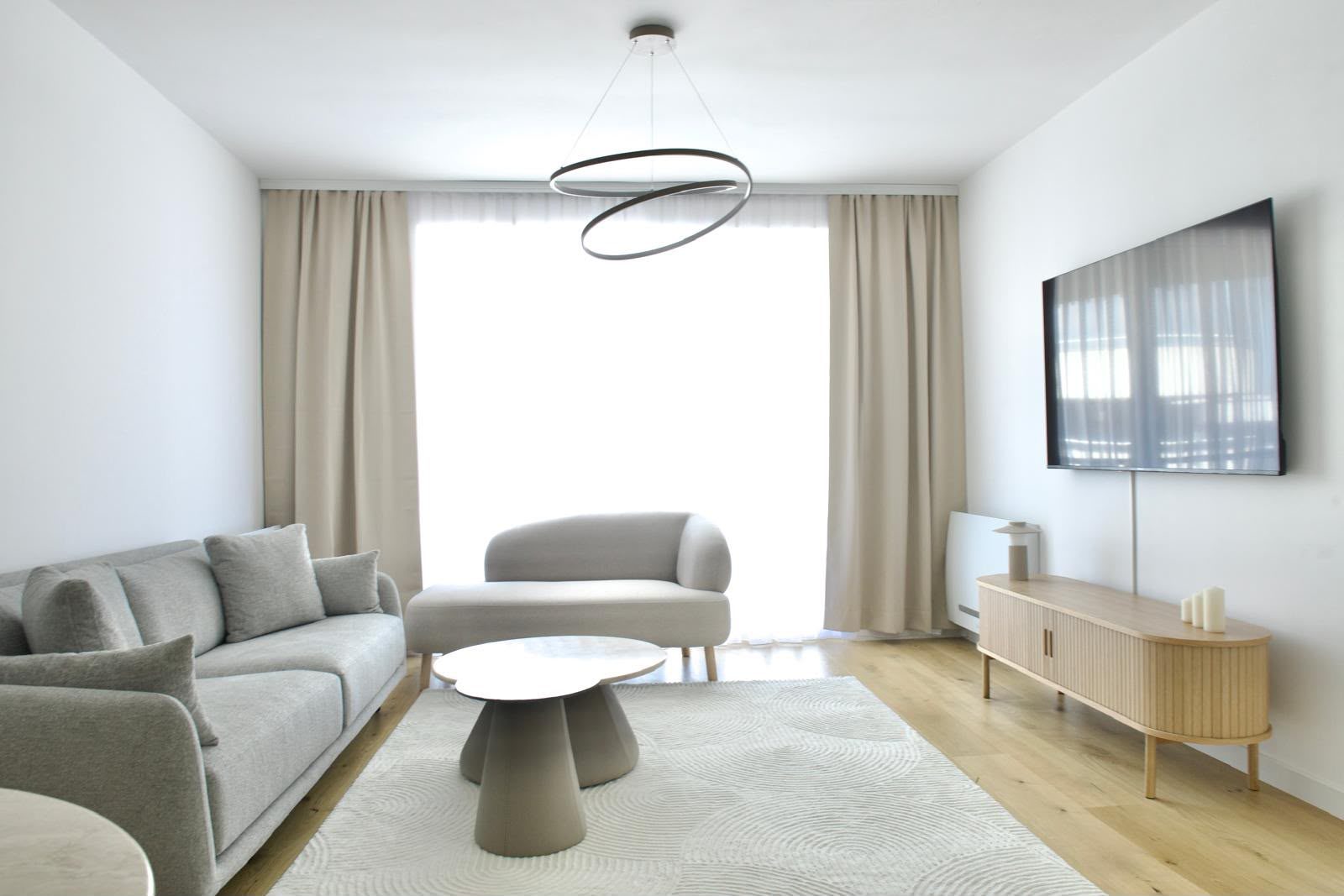 Living room with grey sofa, round coffee table and ring pendant light